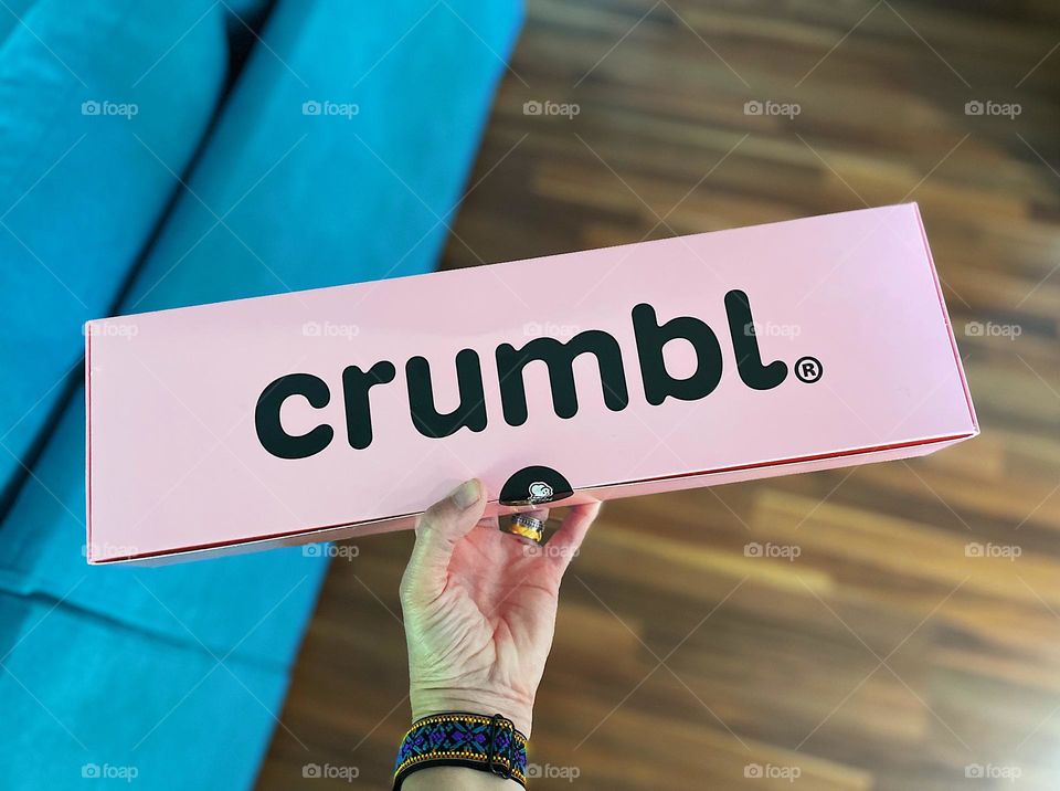 Woman’s hand holds Crumbl cookie box, getting delicious treats delivered, birthday treats delivered 