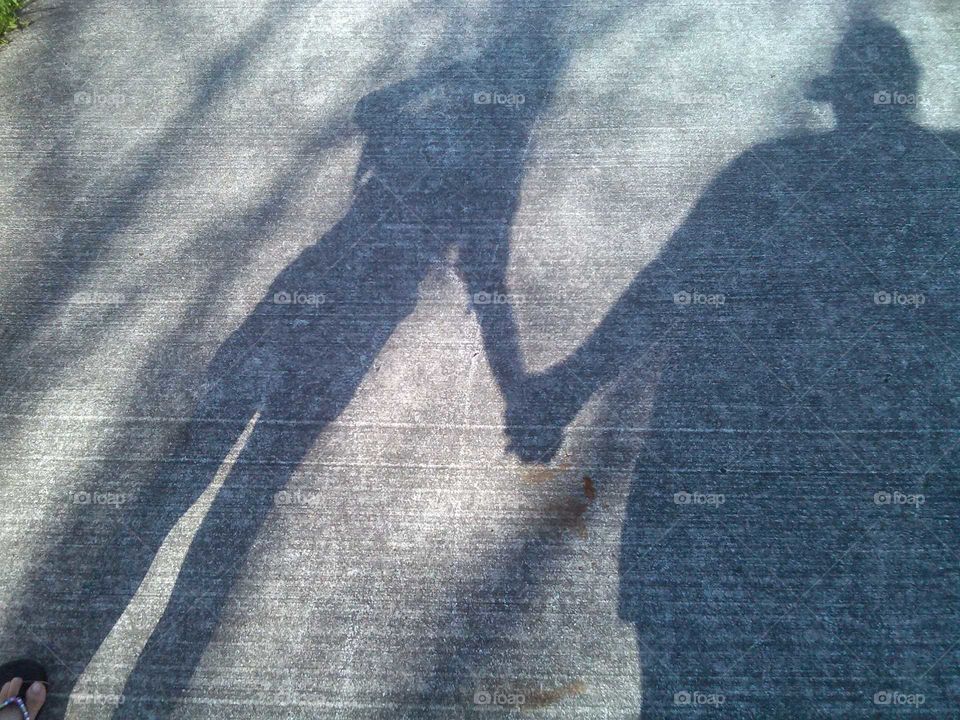 an adult holds the hand of a young child in a shadow