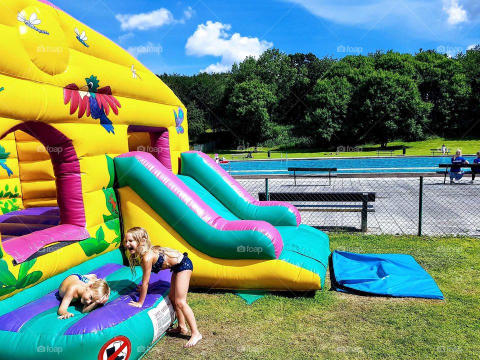 children playing on a colourful bouncing castle by a pool