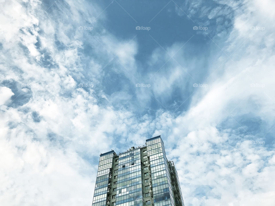 Top view of modern building in front of a blue cloudy sky 