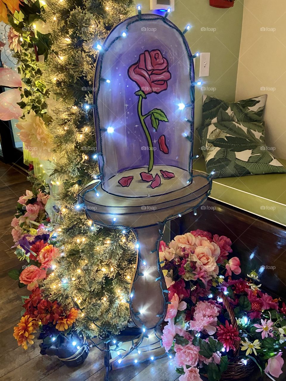 An elegant display with a rose in a glass jar and strings of lights and colorful flowers