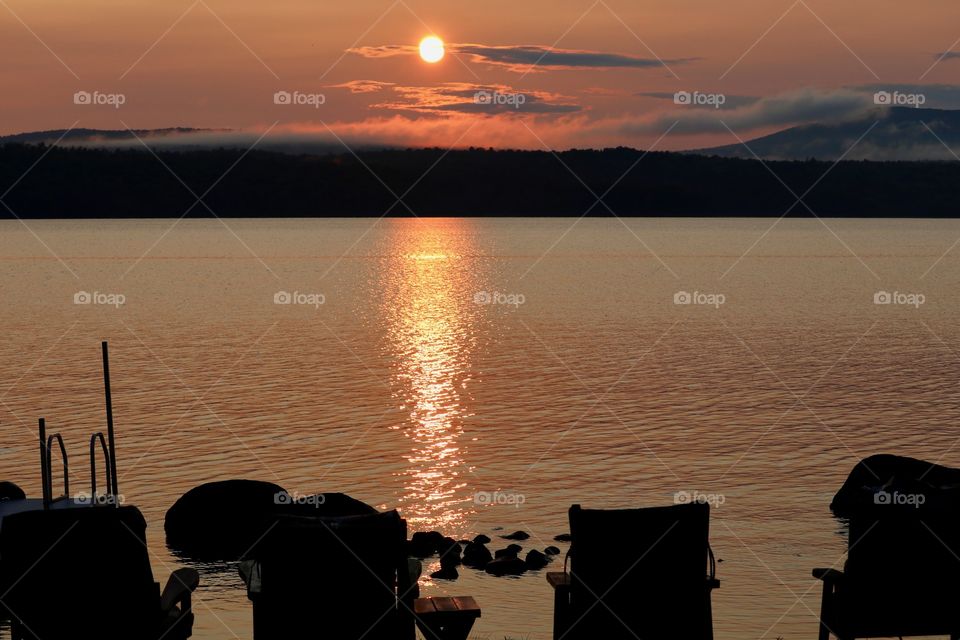 Lawn chairs by the lake at sunset 