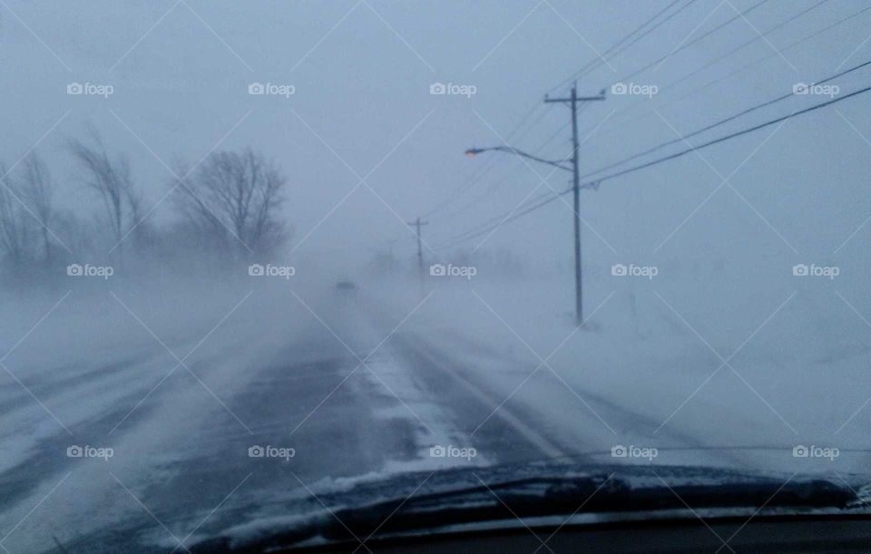 View of a snowy and road with poor visibilty cause by big winds