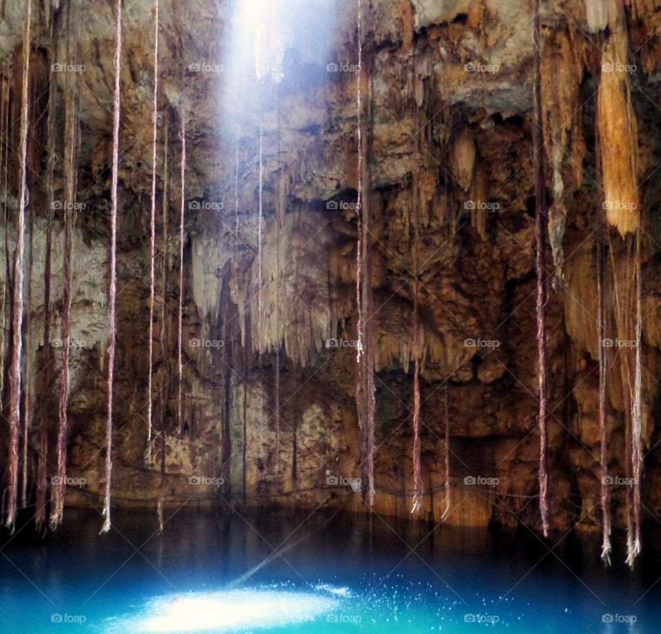 Sunlight shining through hole in a cave on water