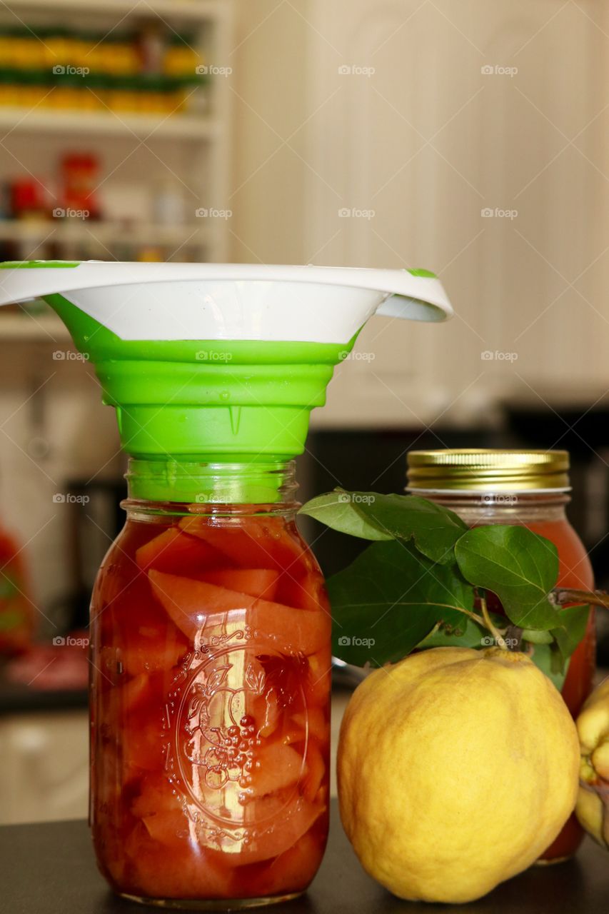 Preparing and filling the jars for homemade quince fruit preserves and sauce 