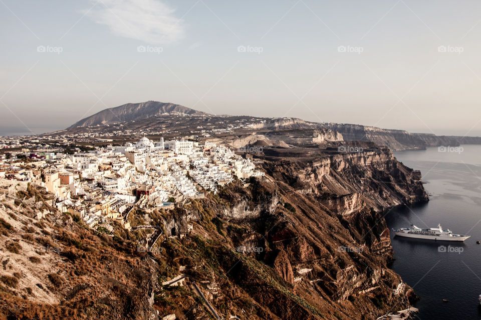 Santorini on cliff by sea against clear sky