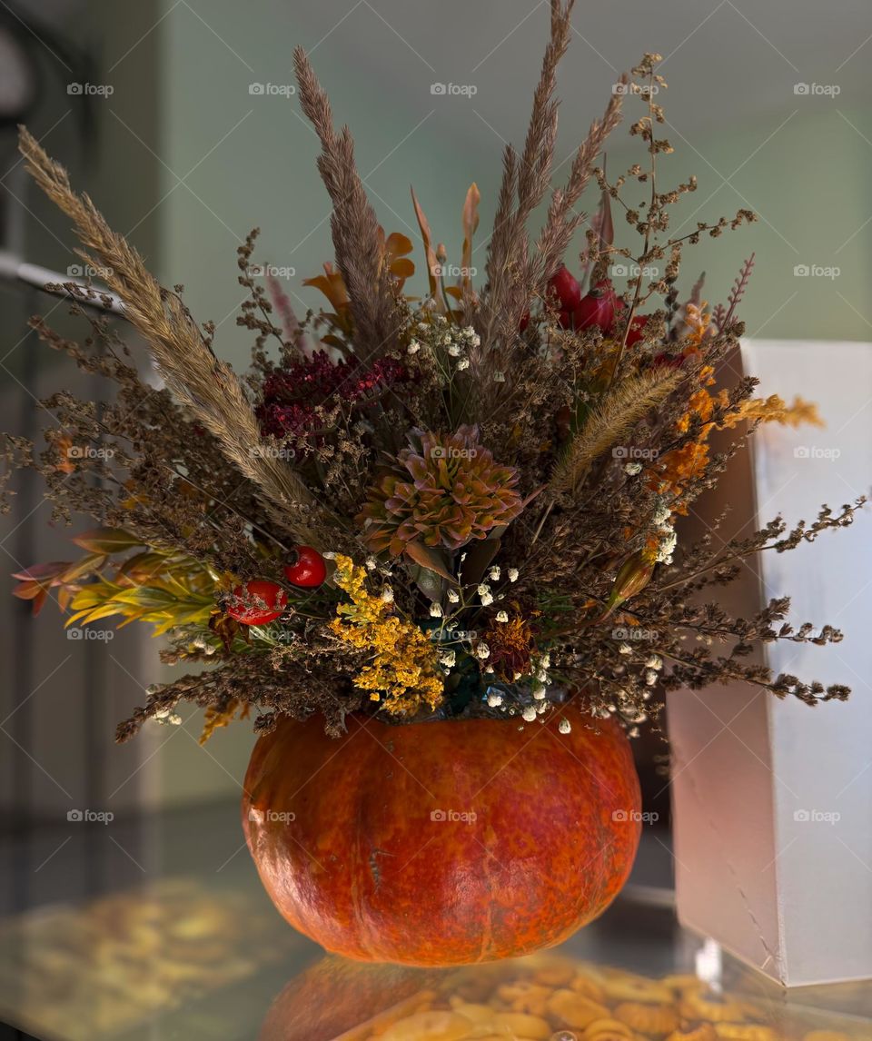 Autumn bouquet with dried and fresh flowers and herbs in the bright orange pumpkin 