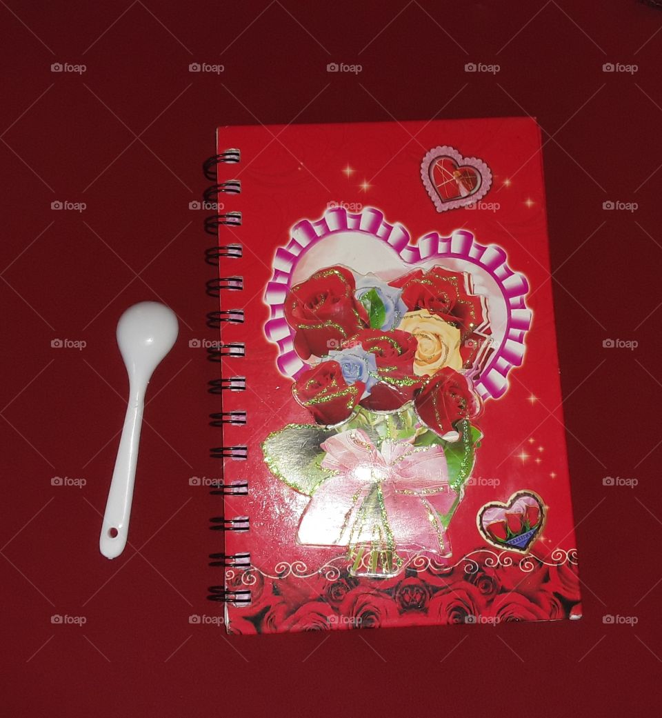 beautiful red book and spoon in this picture. background is red. it is very colourful picture.