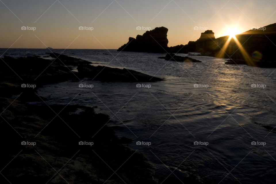 sunset over rocky coastline