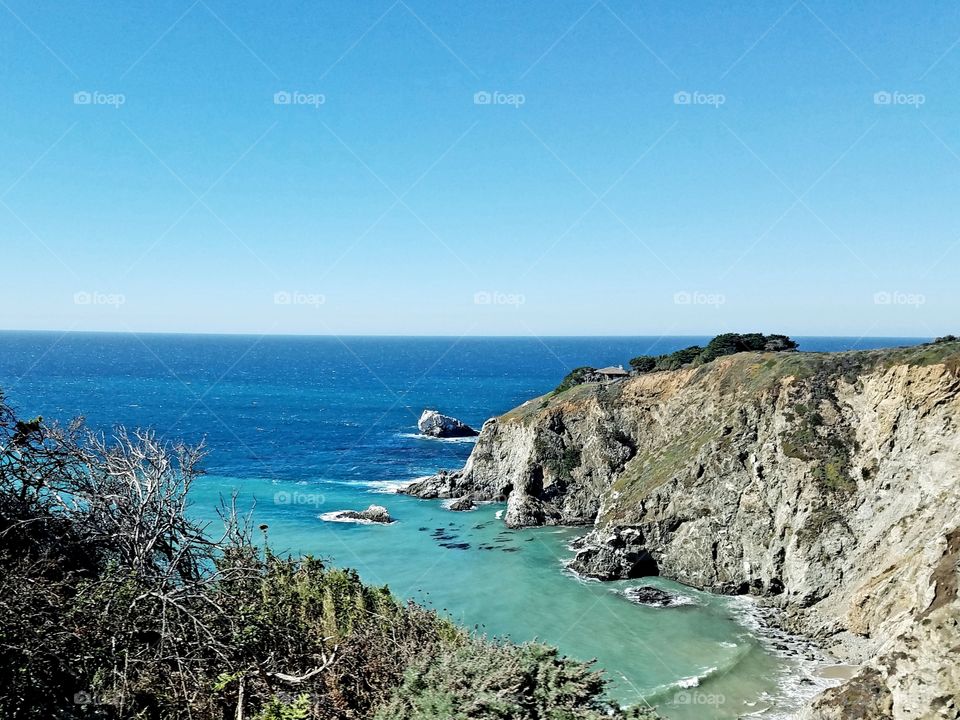 Vibrant blue or the ocean as it rolls into the shore along the rocky coastline.