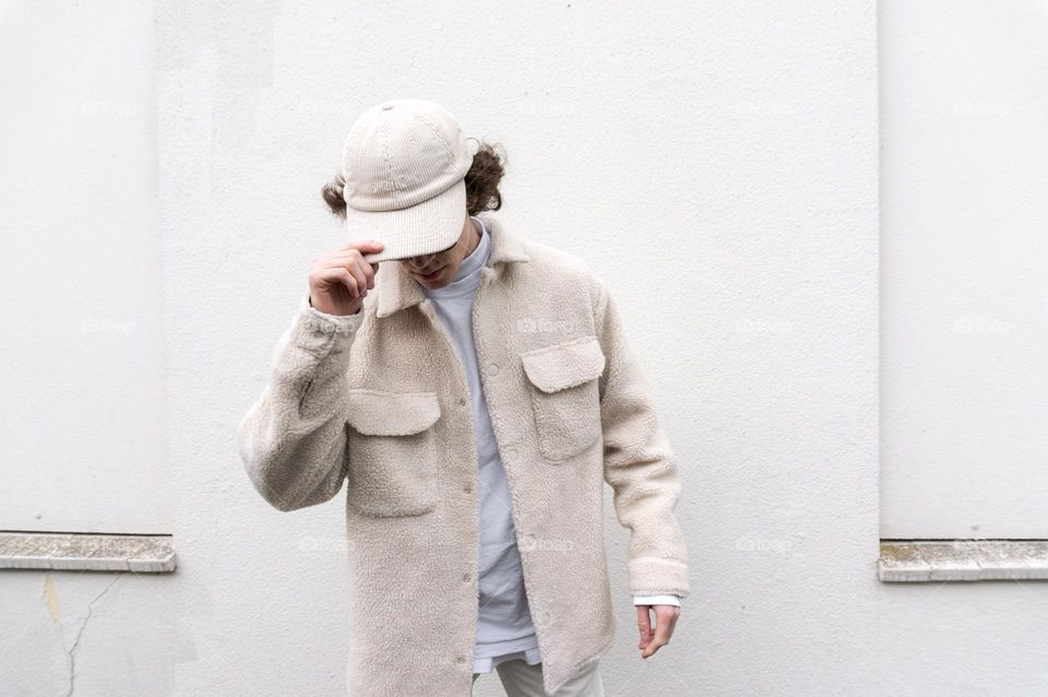 Boy dressed in white clothes standing in front of a white wall