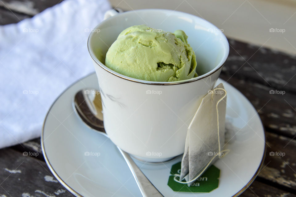 Scoop of green tea ice cream in a teacup and saucer