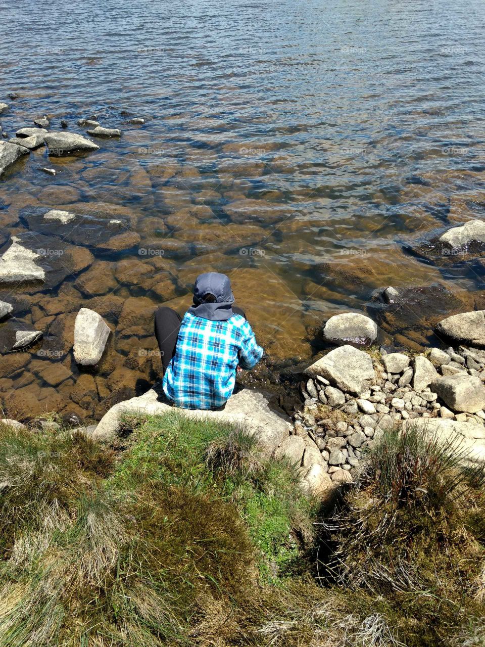 Boy sitting at Lake shore.