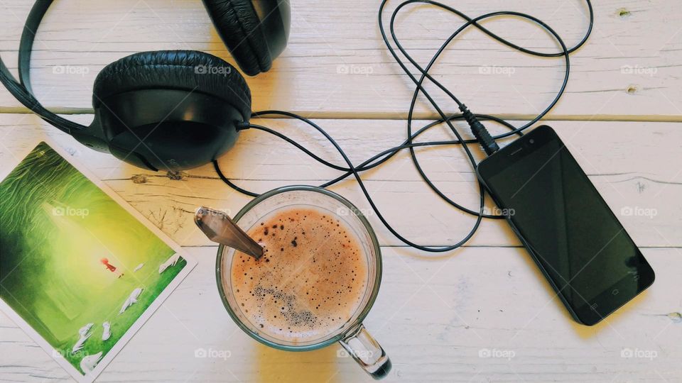 cup of coffee, smart phone, headphones on table