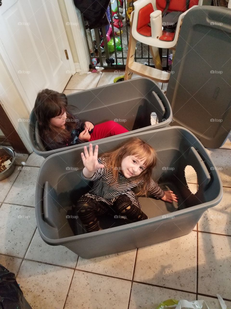 Two Little Girls playing in two boxes/ tubs.