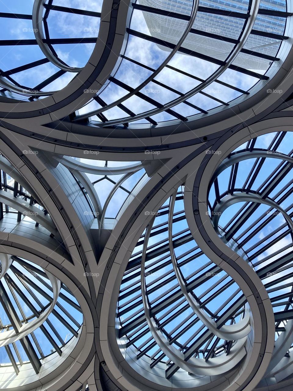 Looking up at blue sky through pattered ceiling 