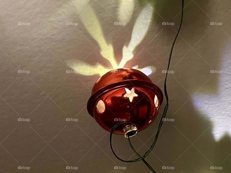 Red Christmas bell lightmaking reflections on a wall