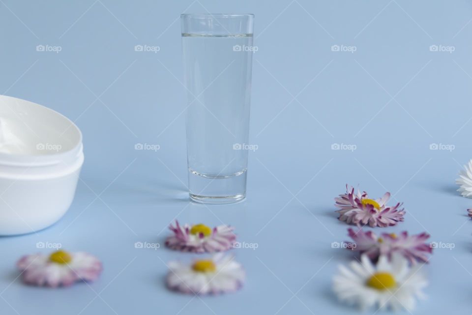 Jars with cosmetic products, beauty cosmetics in a white jar with cream and water with fragrant flowers.