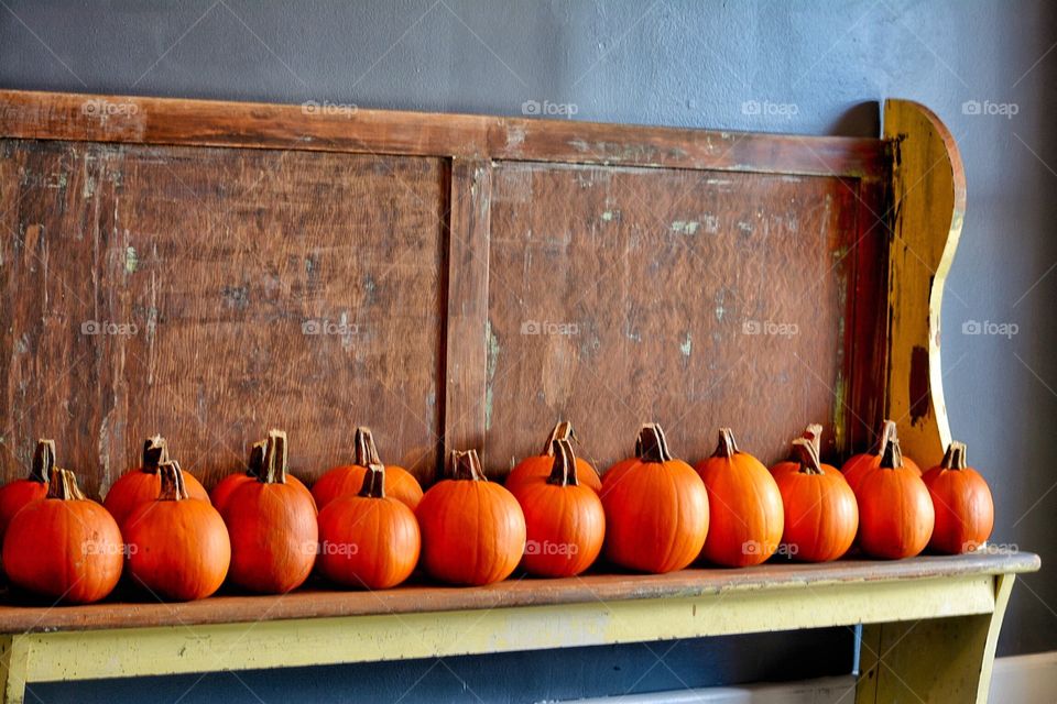 Pumpkins for sale arranged on a old church pew