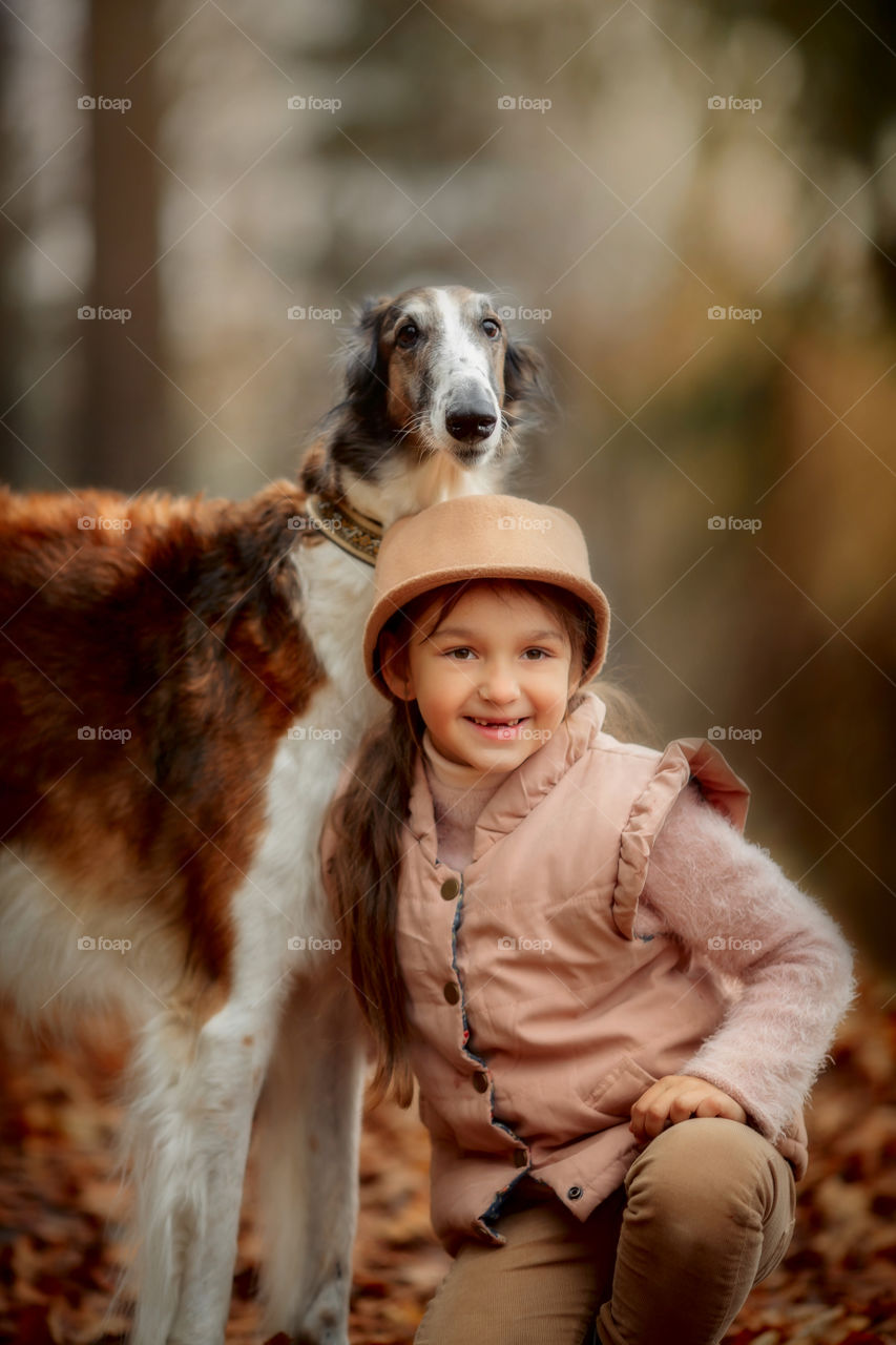 Cute smiling girl with borzoi dog in an autumn park 