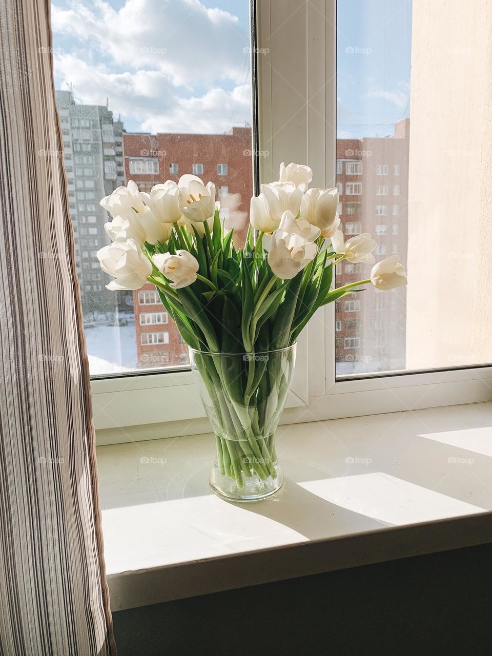 Bouquet of flowers tulips in vase on window sill at home 