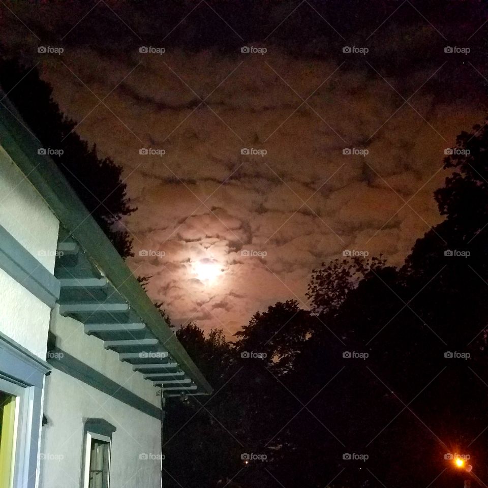 full moon hiding behind the clouds