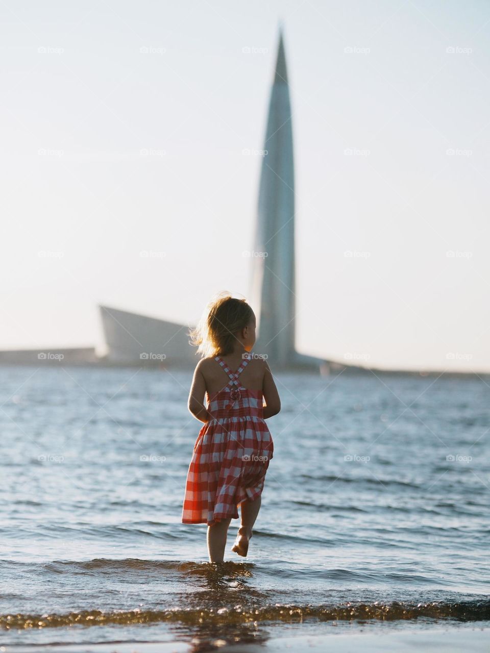 Cute little girl near water in urban, back view 