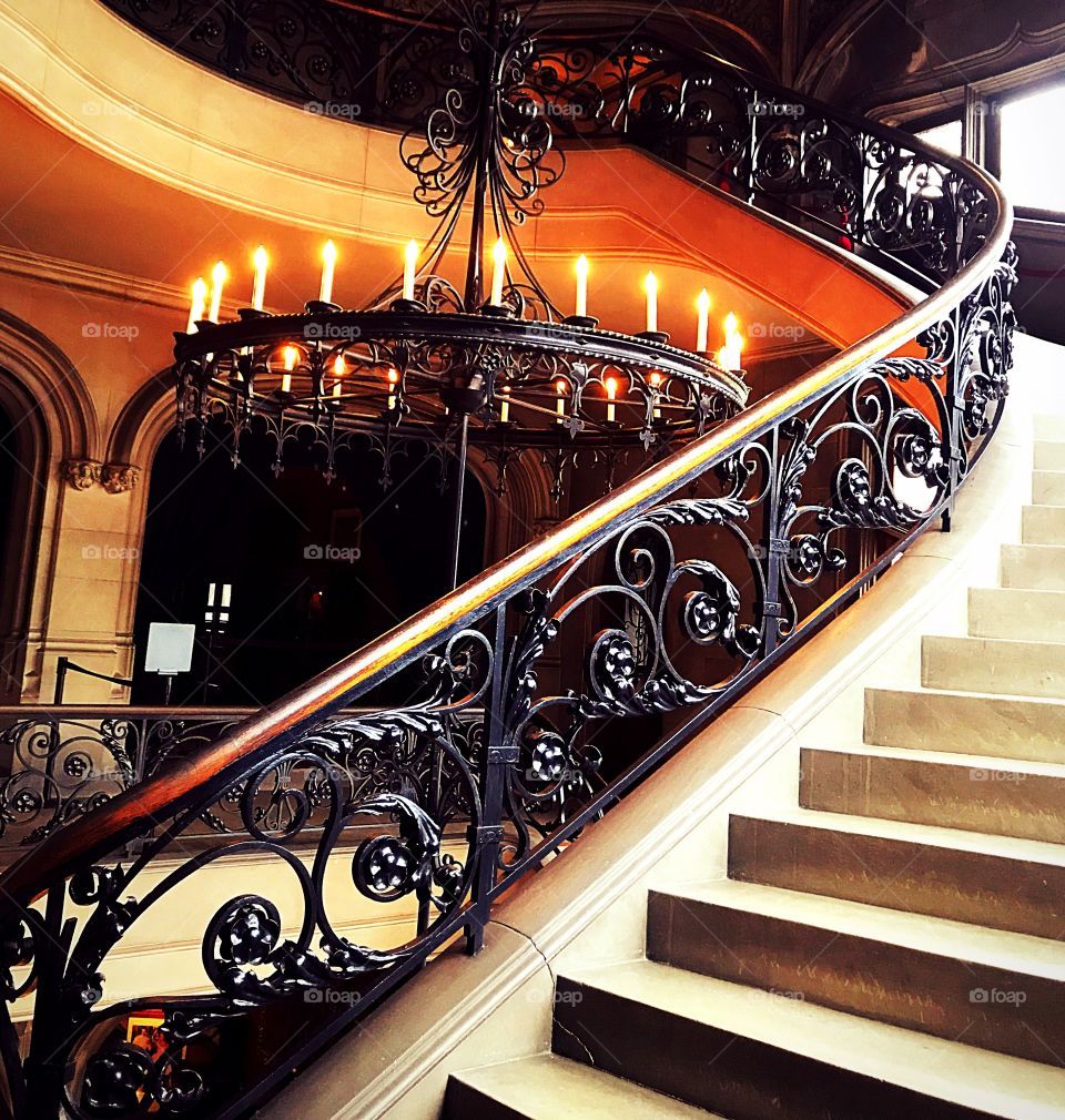 Candlelit staircase in castle with ornate wrought iron rails 