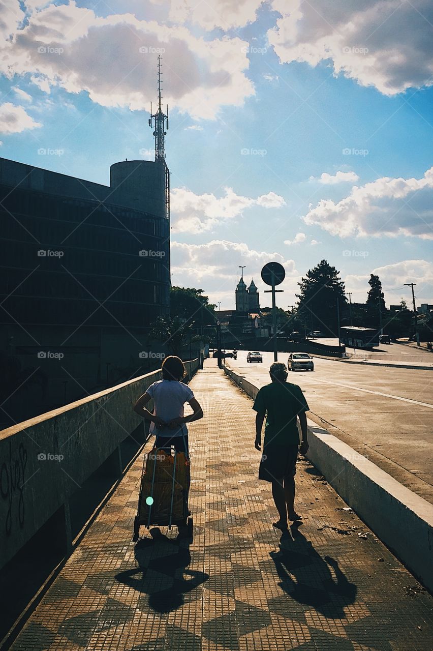 Two people crossing a bridge on sunset time