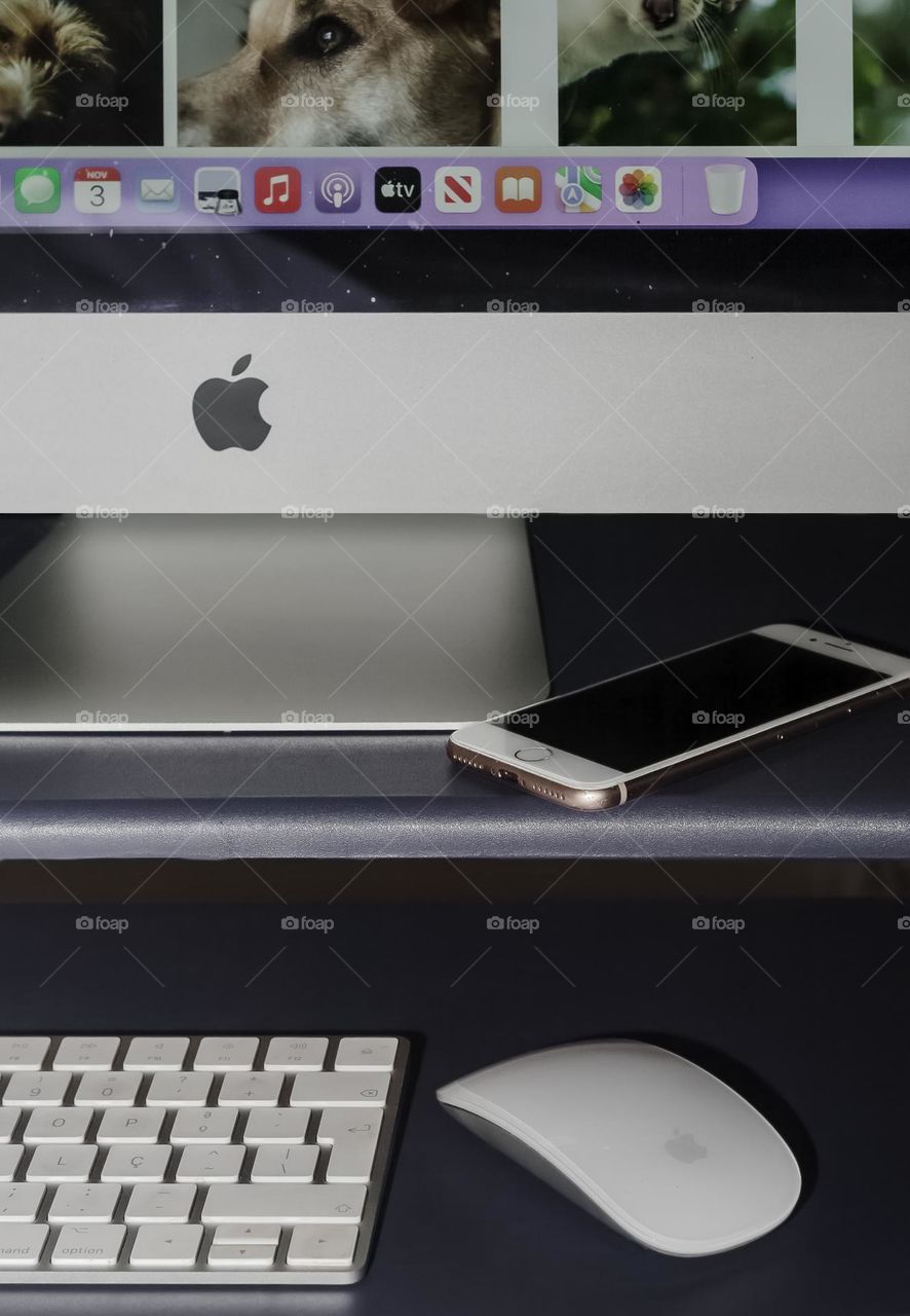 View of a desk with a partial view of and iMac screen, with iPhone, keyboard & mouse