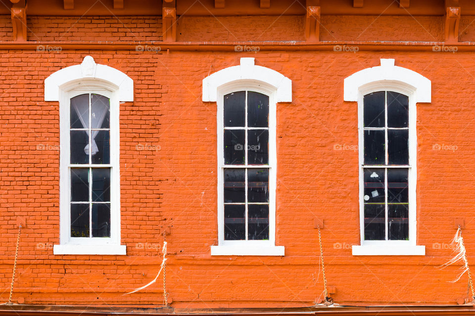 Orange brick house facade and three white window trim