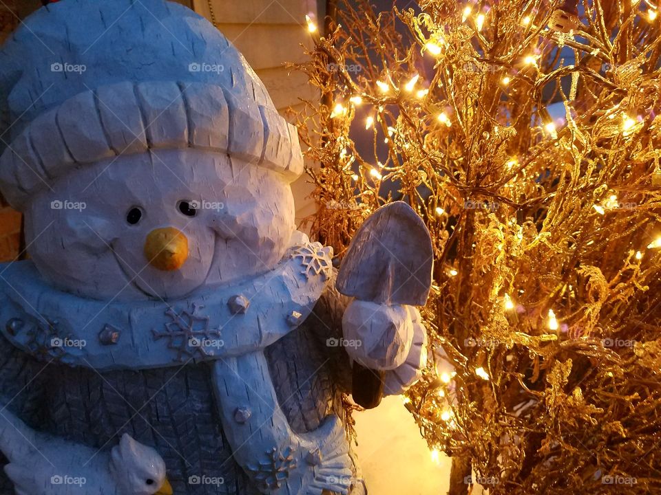 Snowman statue next to ice bush