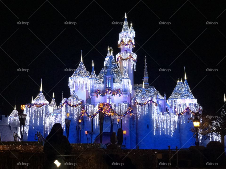 The beautifully lit Disneyland castle during the Christmas season just after fireworks