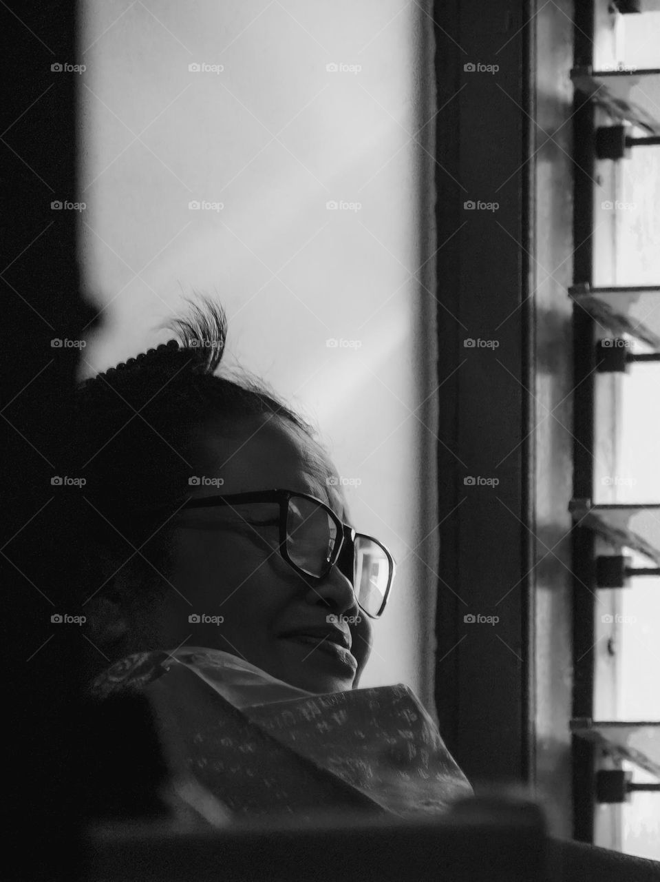 Close-up view of an artistic portrait of a woman in glasses with a smiling mouth. This photo uses black and white and light and shadow effects to create a dark and mysterious atmosphere. This photo is intended to convey a message and expression