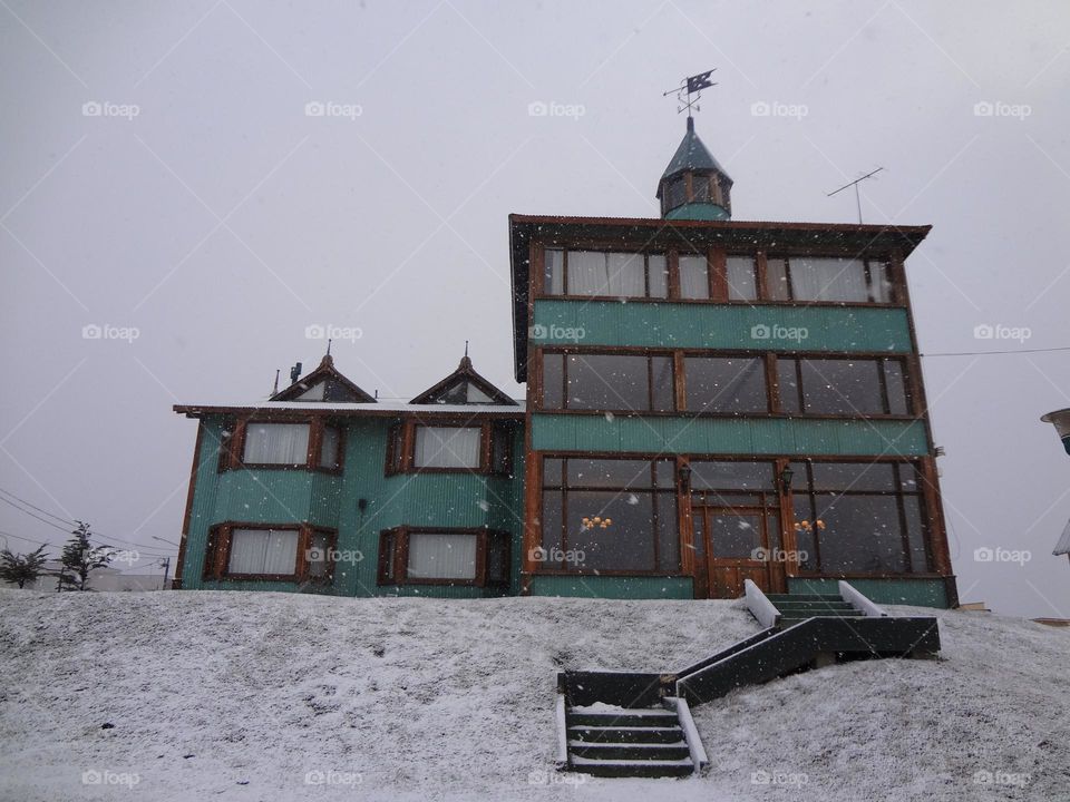 Facade of a green wooden house in a snowy day