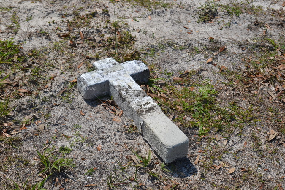 A fallen concrete cross in a cemetery 