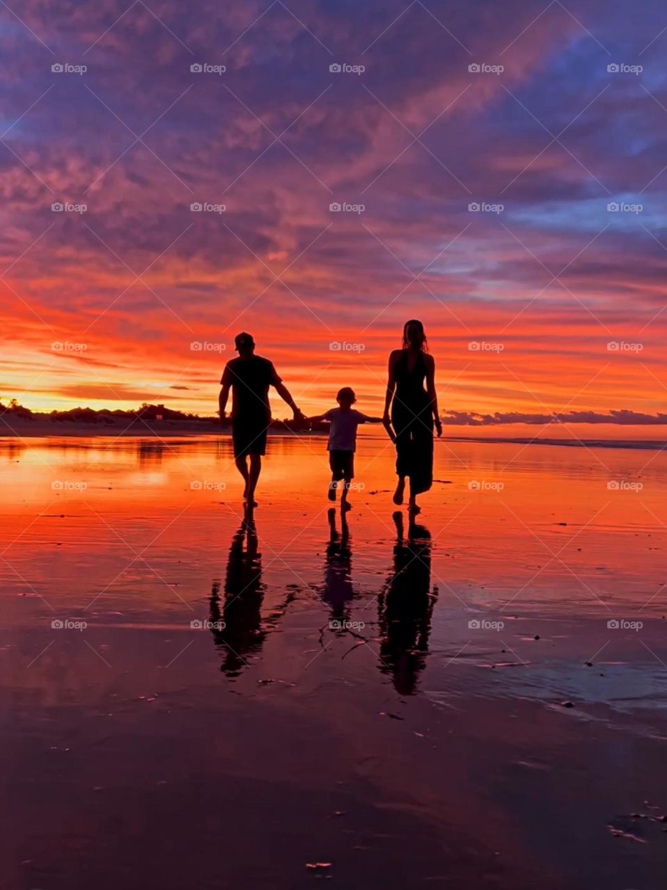 Family walking on the beach at sunset