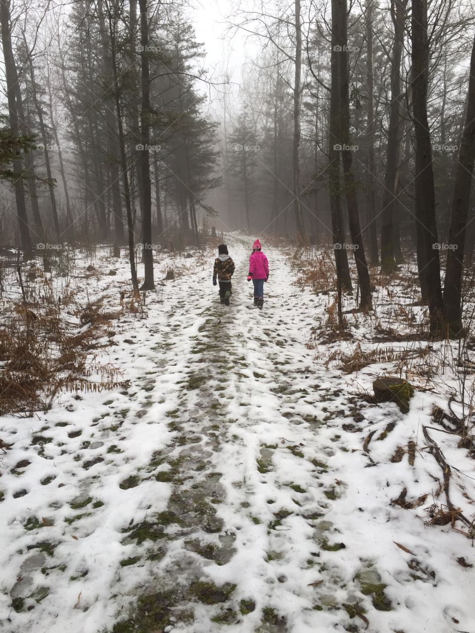 Side by Side. Brother and sister walking through snowy woods