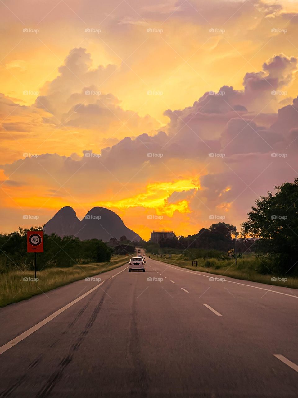 Sunset view of a rural road with beautiful scenery of the orange and pink clouds and hills