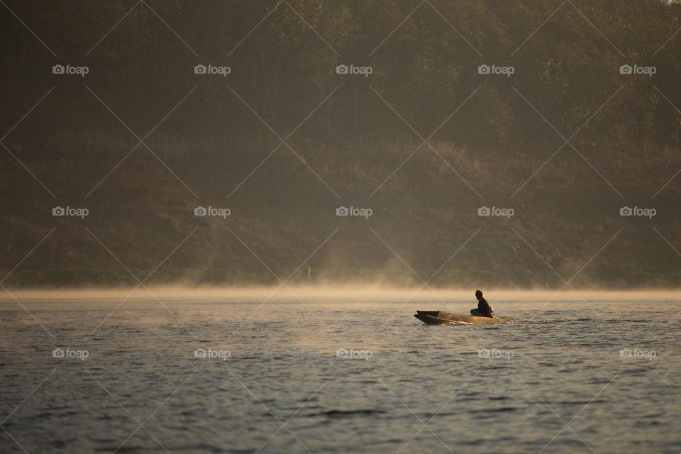 Man riding boat in the river with mist