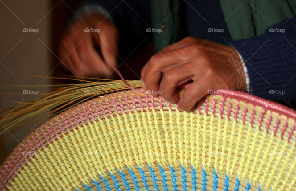 Man weaving a rug with natural materials