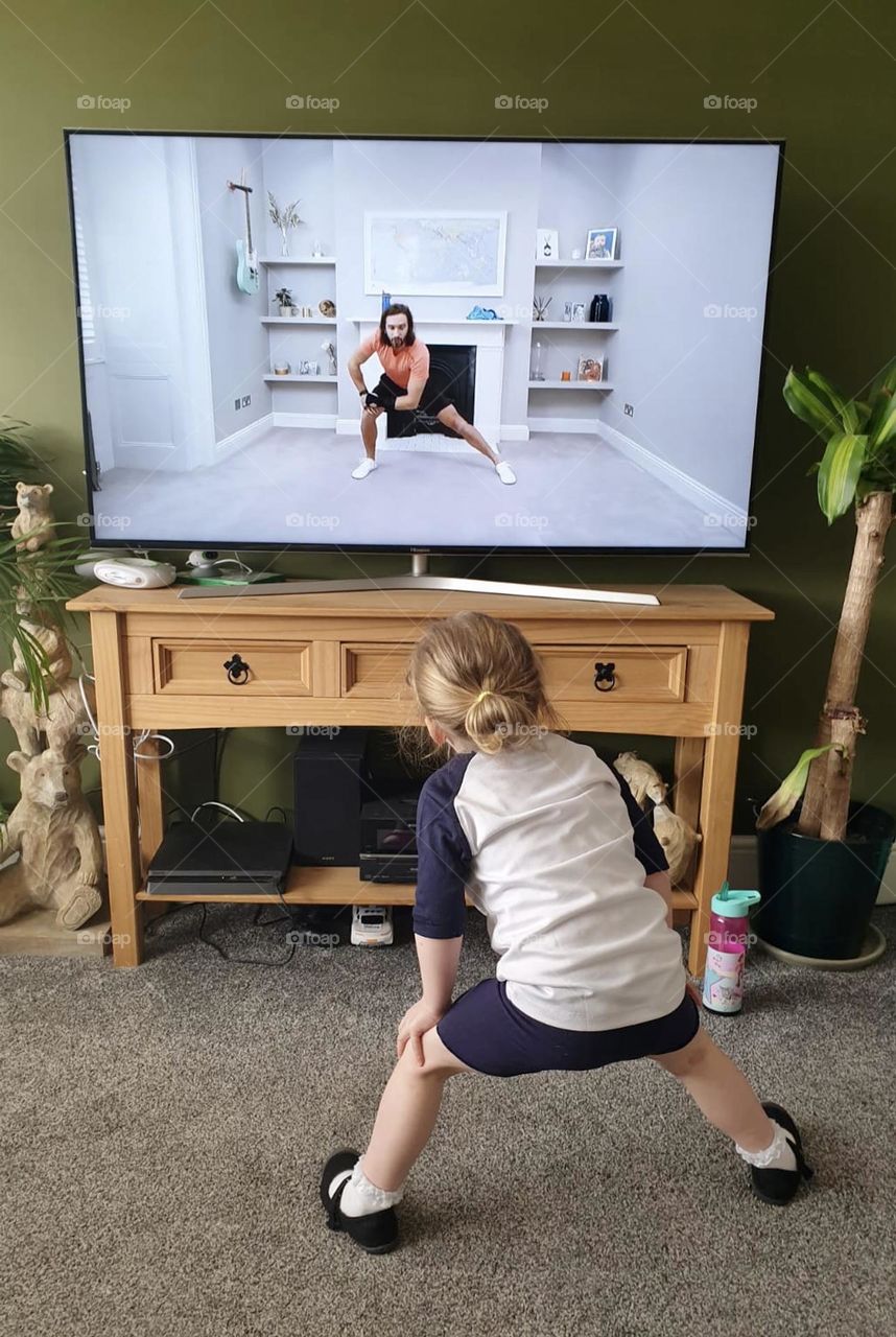 Watching the television and trying to copy the presenter exercising 