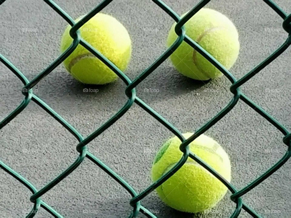 Green fence and tennis balls