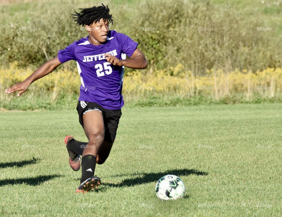 Young man running to kick a soccer ball