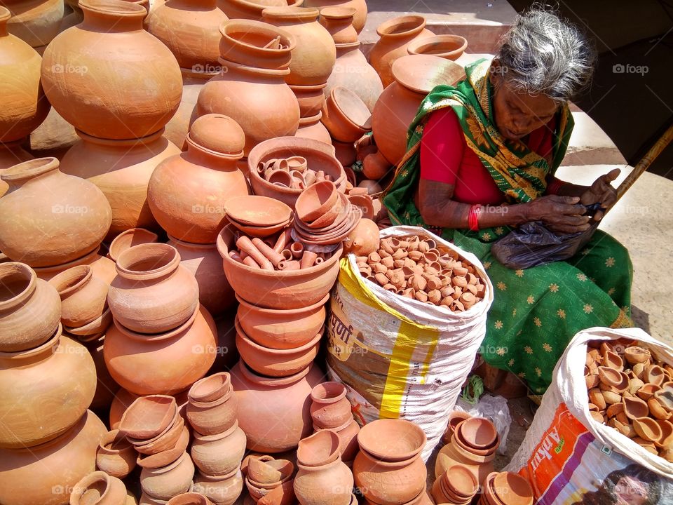 An indian old women selling clay pots in summer on the street side.
