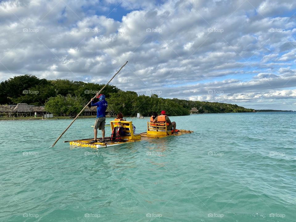 A raft being poked across a beautiful lagoon 