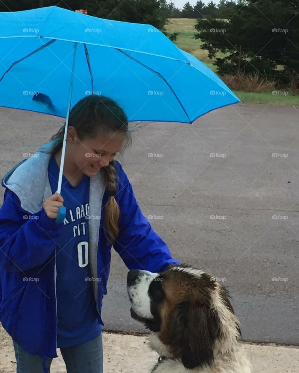 Teenage girl holding umbrella in hand with dog