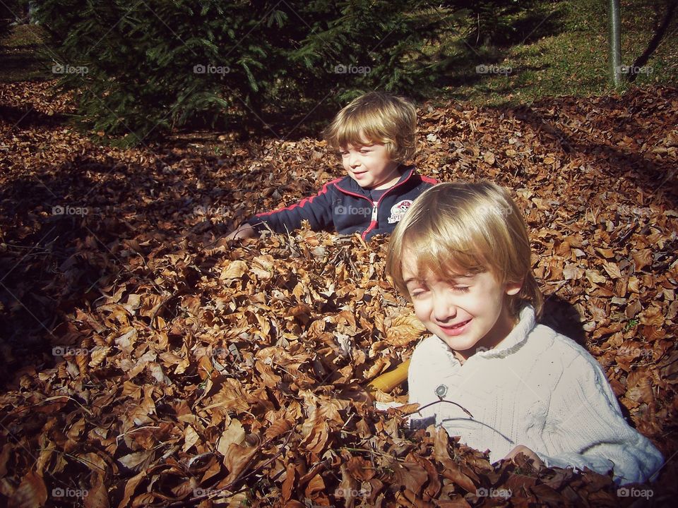 Winter games. Childs playing with the leaves in a forest 
