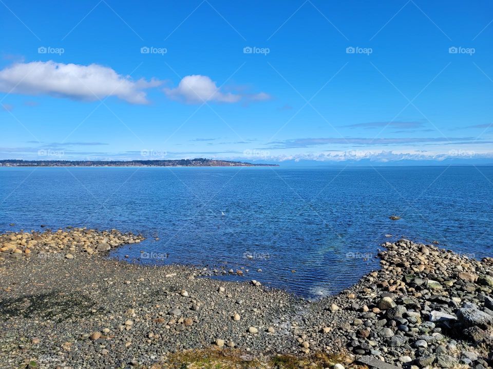 beautiful ocean seascape view of the sand, stones, ocean, land and mountains in British Columbia Canada