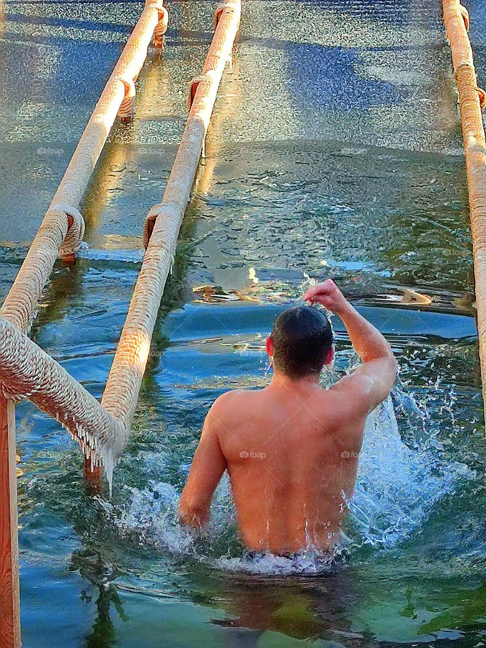 Winter day.  In the hole is a man who has emerged from the water and is being baptized. Baptism of the Lord (Holy Epiphany)